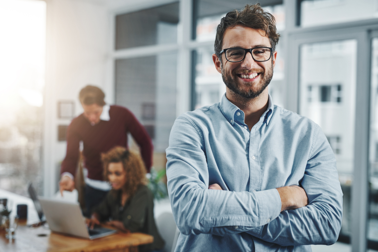 Confident managers create successful teams. Portrait of a confident young man with his colleagues in the background at work. Confident managers create successful teams. Portrait of a confident young man with his colleagues in the background at work.