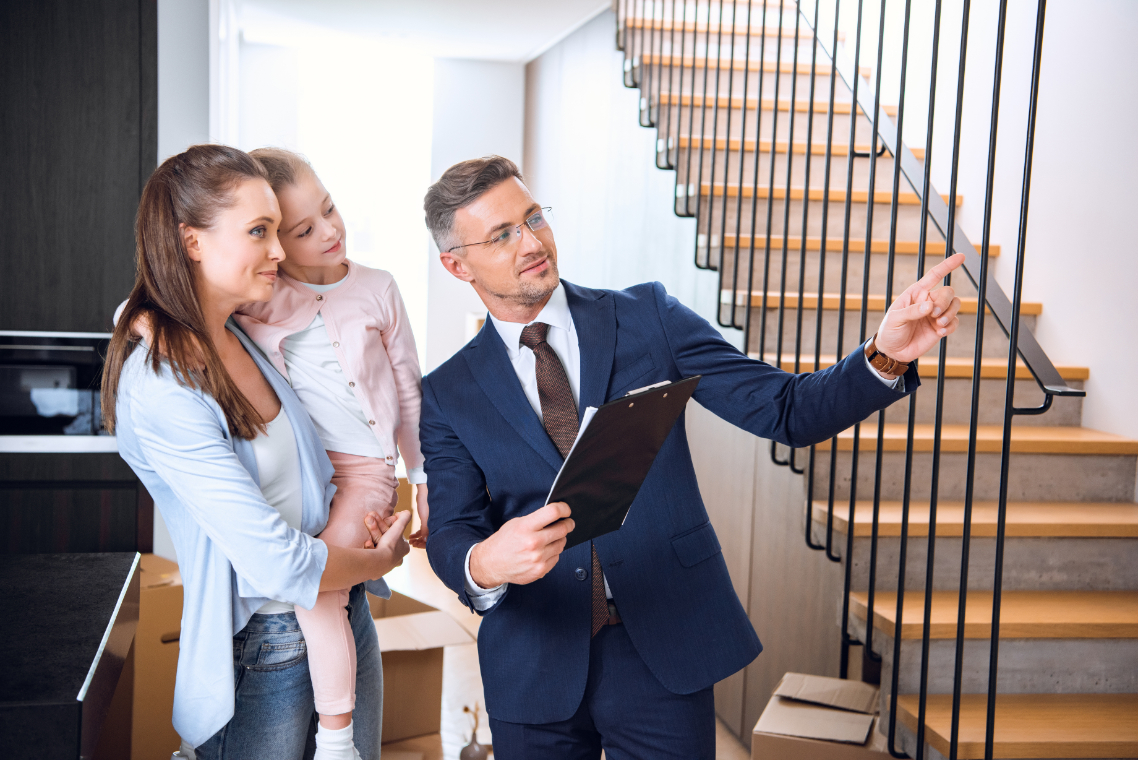 Handsome broker showing something to woman holding in arms cute daughter